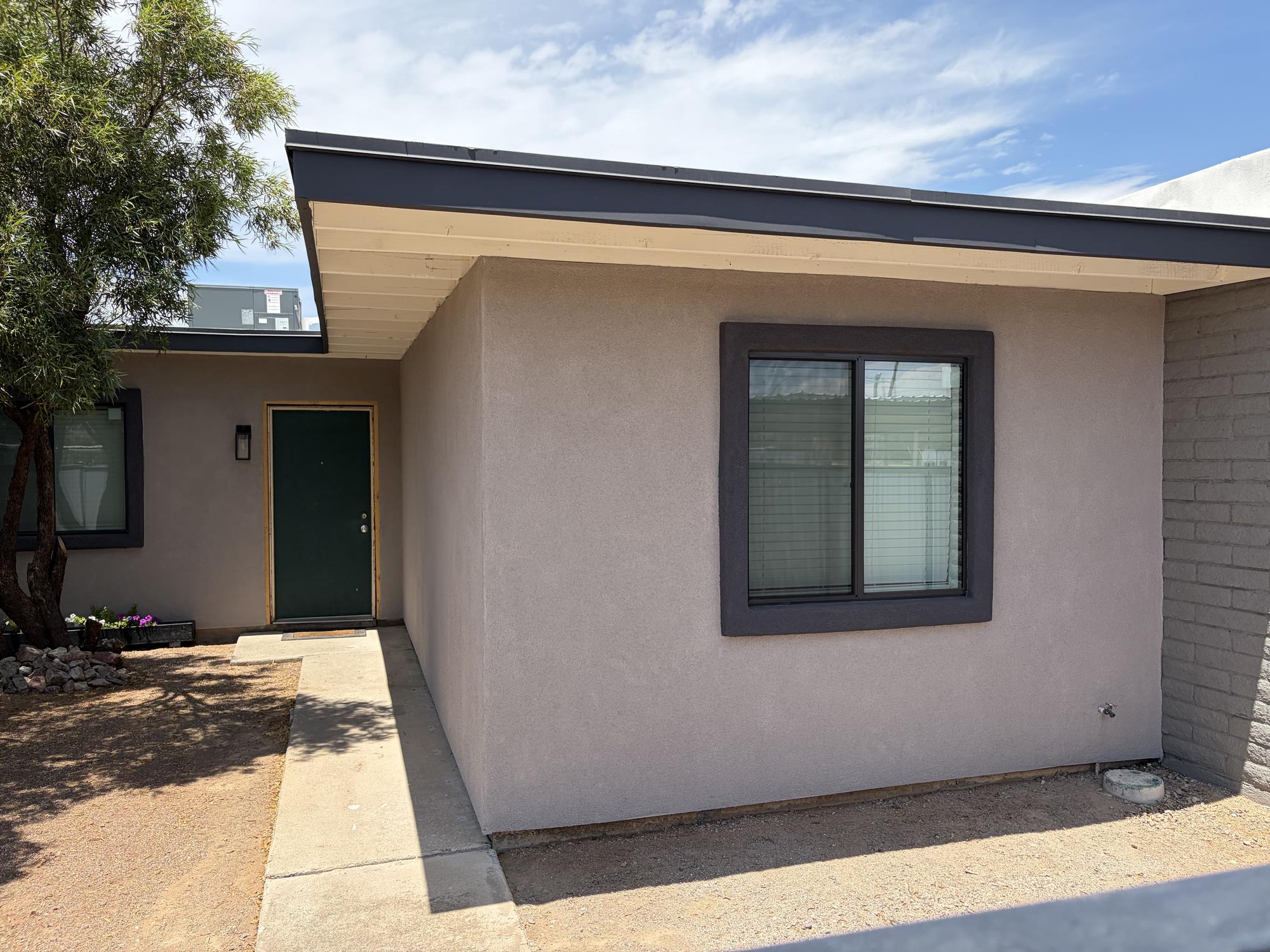 Stucco applied over the mesh on the same apartment complex, showing restoration progress